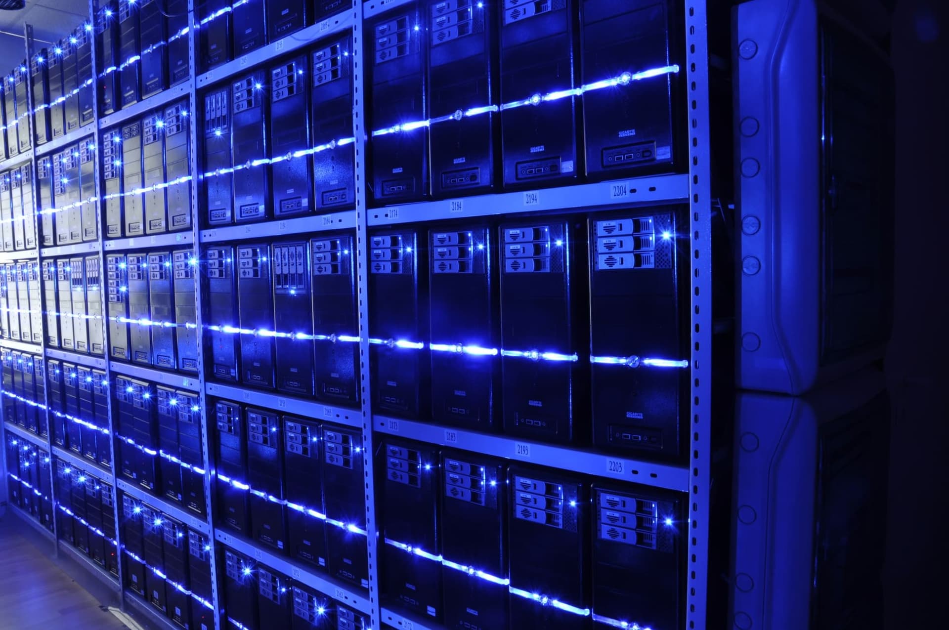 Pareti di server montati in rack in una sala macchine, illuminati da luci LED blu.