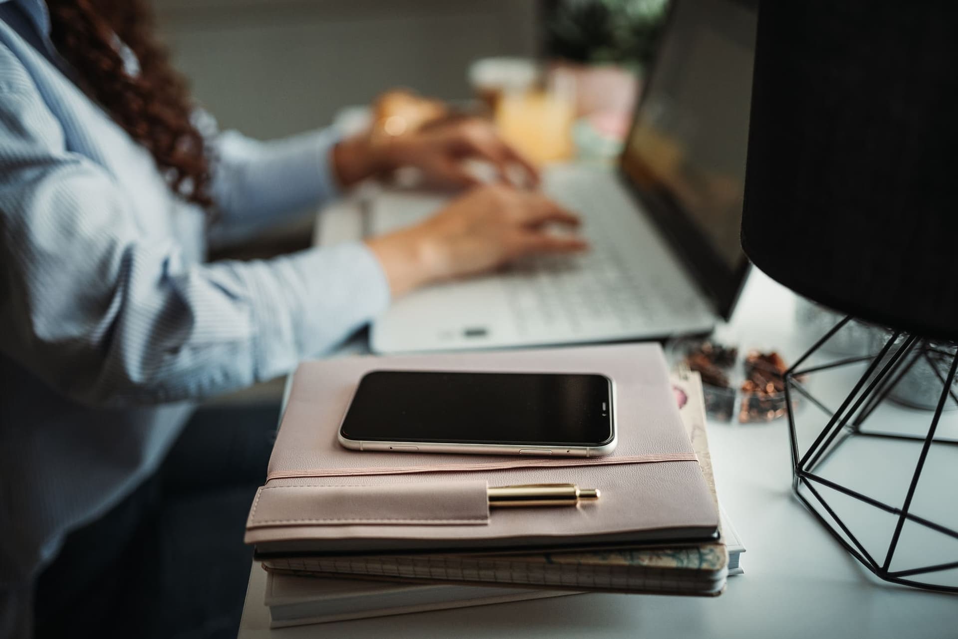 Una persona scrive al portatile su una scrivania con agenda e smartphone