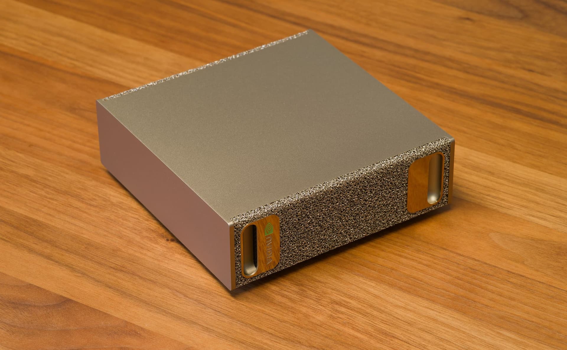 NVIDIA DGX Spark vista di tre quarti: mini computer in alluminio dorato con frontale in schiuma metallica, appoggiato su un tavolo di legno.